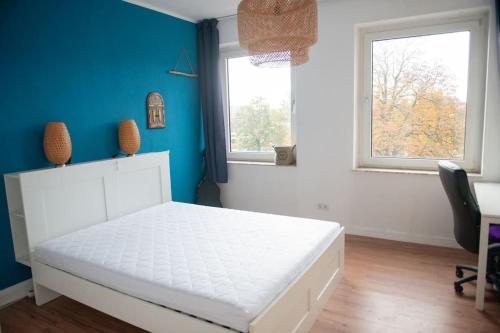 um quarto com uma cama branca e uma parede azul em Ruhige 3-Zimmer-Wohnung Messenah em Hanôver