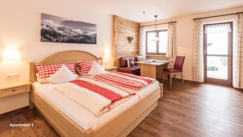 a bedroom with a large bed with a desk and a table at Gschwenderhaus Ferienwohnungen in Oberstdorf