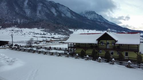a building covered in snow with mountains in the background at Maricom Home in Zărneşti
