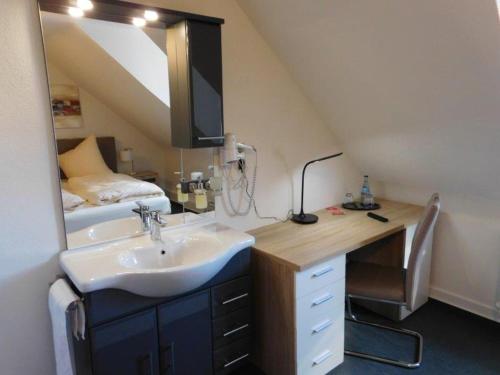 a bathroom with a sink and a mirror and a bed at Hotel Romäus in Villingen-Schwenningen