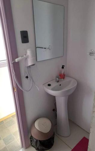 W białej łazience znajduje się umywalka i lustro. w obiekcie Departamentos k&m w mieście Puerto Natales