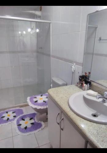 een badkamer met een wastafel, een toilet en een spiegel bij Suíte Praia de Camburi in Vitória