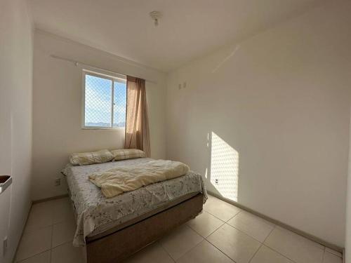 um quarto com uma cama e uma janela em Apartamento em Biguaçu