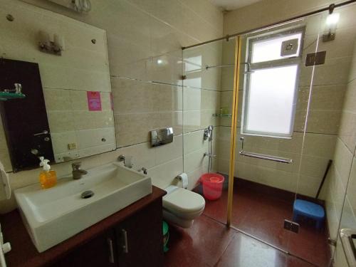 baño con lavabo y aseo y ventana en A Sleepy Fox Hostel, en Nueva Delhi