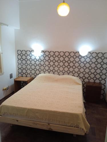 a bedroom with a bed with two lights on the wall at La Perla alojamiento in Mar del Plata