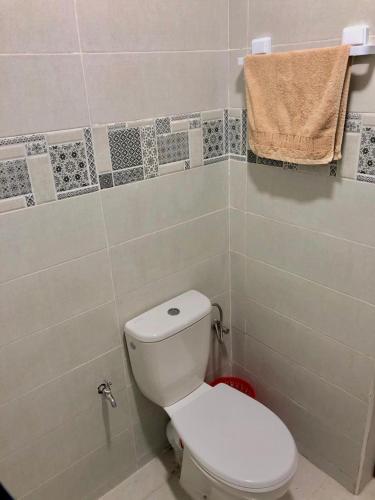 a bathroom with a toilet and a towel on the wall at Apartement au Bord de la Mer TOURMA in Taghazout