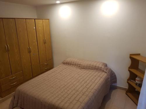 Dormitorio pequeño con cama y armarios de madera en La esquina - Alquiler temporario en Santa Rosa