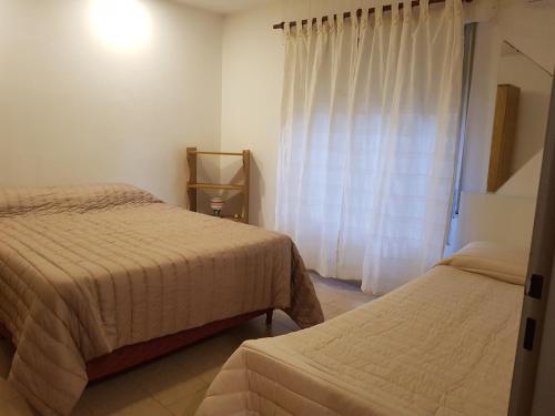a bedroom with two beds and a window with curtains at La esquina - Alquiler temporario in Santa Rosa