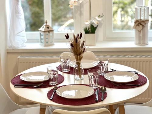 a white table with plates and glasses on top of it at Apartament SASANKA in Kudowa-Zdrój