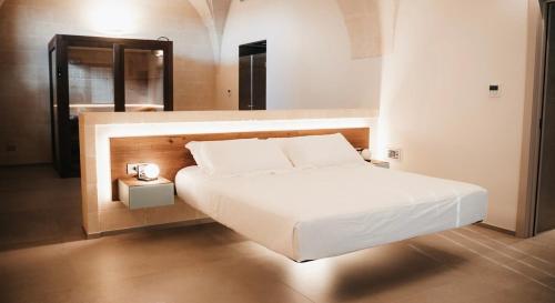 een slaapkamer met een groot wit bed en een spiegel bij MASSERIA ACQUASALE - RELAIS & RESTAURANT in San Giorgio Ionico