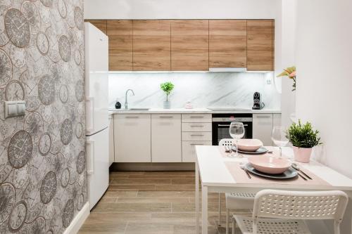 biała kuchnia ze stołem i krzesłami w obiekcie Luxurious Danubeside Apartment for 4 w Budapeszcie