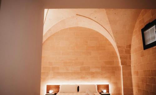 een slaapkamer met een bakstenen muur en een bed met 2 lampen bij MASSERIA ACQUASALE - RELAIS & RESTAURANT in San Giorgio Ionico