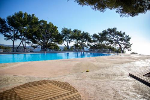 une piscine vide avec des arbres en arrière-plan dans l'établissement Cadre exceptionnel - Appt Classé 3 entièrement climatisé - Mer-piscine-tennis, à Bandol