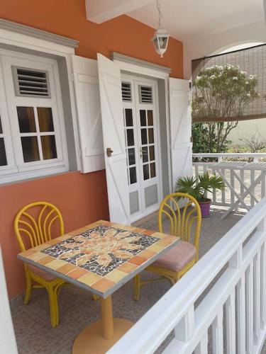 a table and chairs on a balcony with a table and chairs at Logement « Alpinia » in Capesterre-de-Marie-Galante