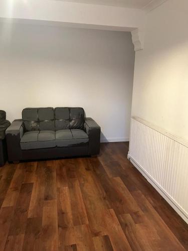 uma sala de estar com um sofá preto no canto em Dagenham Budget House em Dagenham