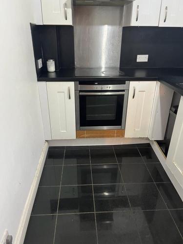 a small kitchen with white cabinets and a microwave at Dagenham Budget House in Dagenham