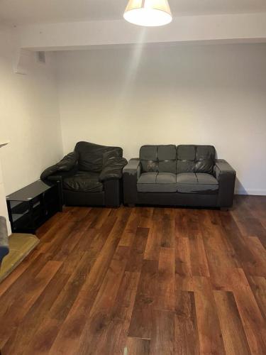 uma sala de estar com um sofá e pisos em madeira em Dagenham Budget House em Dagenham