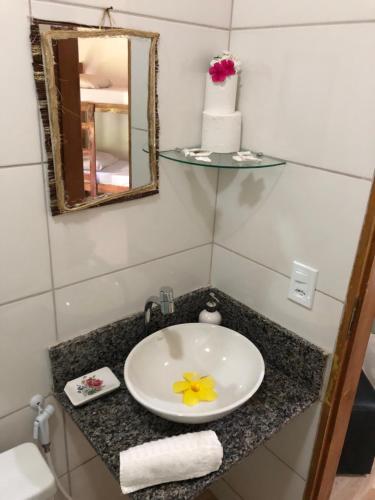 a bathroom with a sink with a yellow flower on it at Village verde in Itacaré