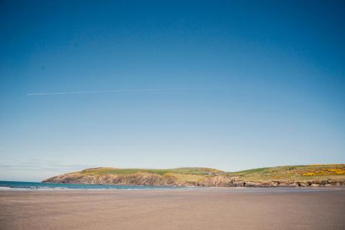 a beach with a view of the ocean and cliffs at Ysgubor - The Barn in Newchapel