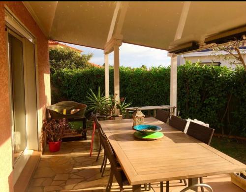 einen Holztisch auf einer Terrasse unter einem Sonnenschirm in der Unterkunft Villa Piscine Mer 66 in Saint-Laurent-de-la-Salanque