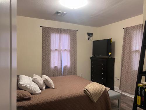 a bedroom with a bed with pillows and a television at Simplicity Stays NOLA in New Orleans