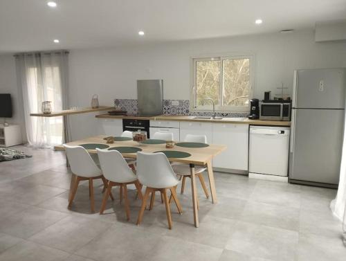 a kitchen with a table and chairs and a refrigerator at Maison 115 m 2 avec Jardin in Carignan