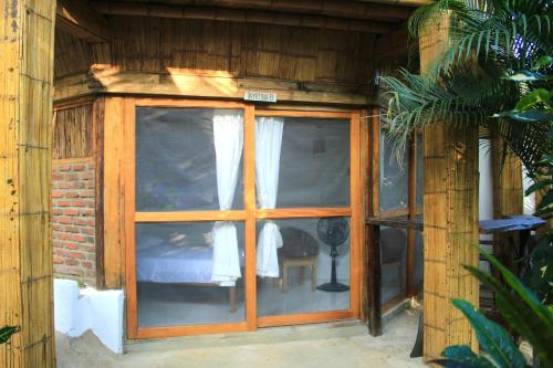 Habitación de madera con ventana y cama. en Hierba Buena Eco Hostel, en El Zaino