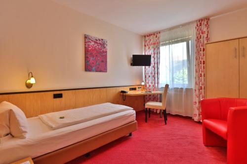 バート・メルゲントハイムにあるApart Hotel Deutschmeisterのベッド、椅子、デスクが備わる客室です。