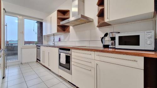 a kitchen with white cabinets and a microwave at T&K Apartments - 3 - 5 Group Room Apartments- 15min to Fair DUS in Neuss