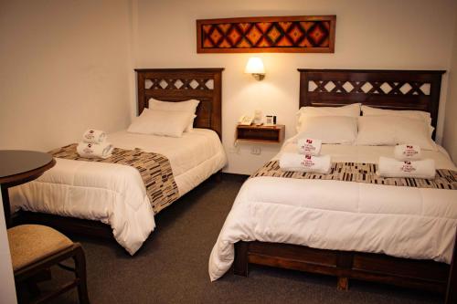 Habitación de hotel con 2 camas y mesa en El Portal Del Marques, en Cajamarca