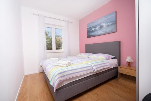 um quarto com uma cama com paredes cor-de-rosa e uma janela em Apartments Oriana em Rabac