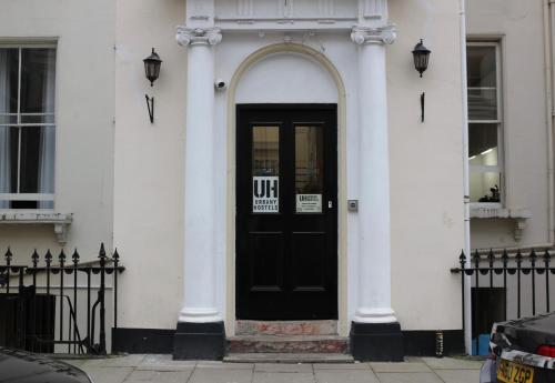 a black door on a white building with a sign on it at Urbany Hostel London 18-40 Years Old in London