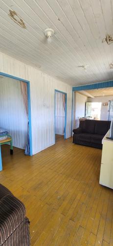 a living room with a couch and a wooden floor at Casa de praia - Descanse e tenha uma experiencia relaxante a poucos metros da praia in Arroio do Silva