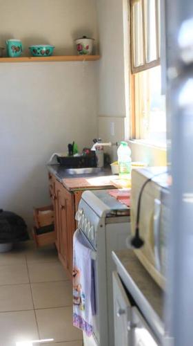 a small kitchen with a stove and a sink at Casa de praia - Descanse e tenha uma experiencia relaxante a poucos metros da praia in Arroio do Silva