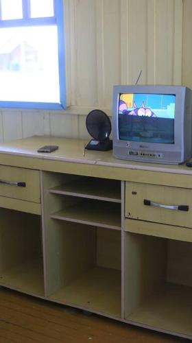 a desk with a tv on top of it at Casa de praia - Descanse e tenha uma experiencia relaxante a poucos metros da praia in Arroio do Silva