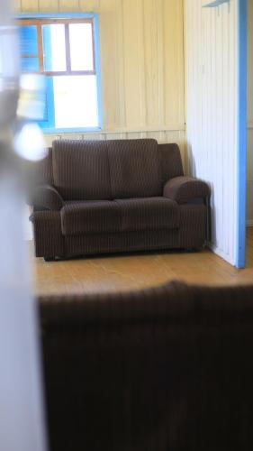 a brown couch in a living room with a window at Casa de praia - Descanse e tenha uma experiencia relaxante a poucos metros da praia in Arroio do Silva