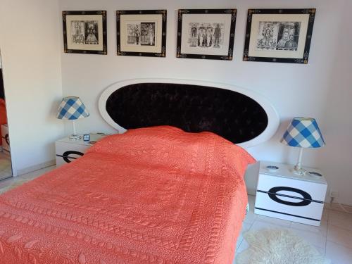 a bedroom with a bed with a red blanket and pictures on the wall at APPARTEMENT AU CALME in Menton