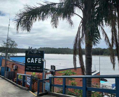 a cafe sign with a palm tree and water at Bondi Breeze @ Tuross Head in Tuross Heads