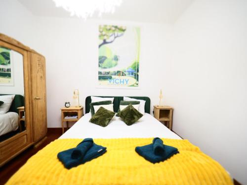 - 2 chaussons bleus sur un lit dans une chambre dans l'établissement LE PATIO LAFAYETTE Appartement de Standing coeur de ville, à Vichy