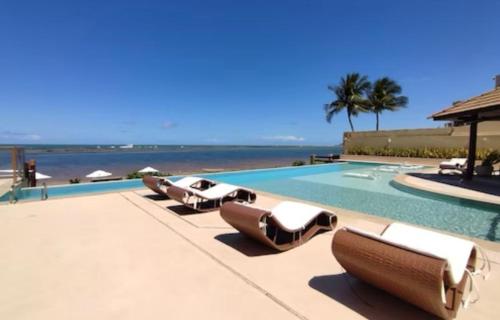 a row of lounge chairs next to a swimming pool at Barra Bali Beach Service 323 BARRA DE SÃO MIGUEL in Barra de São Miguel