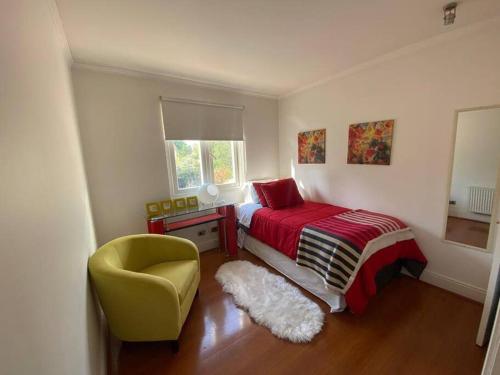a bedroom with a bed and a yellow chair at Casa Amoblada en chicureo in Chicureo Abajo