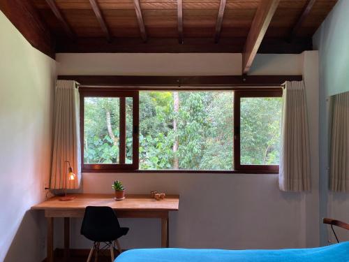 a bedroom with a desk and a window and a bed at Casa Cacau Boutique B&B - Sítio Salamandra Vale do Matutu in Aiuruoca