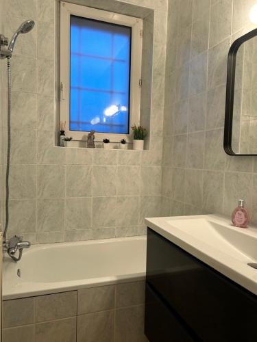 a bathroom with a tub and a sink and a window at Home Lyla in Dijon