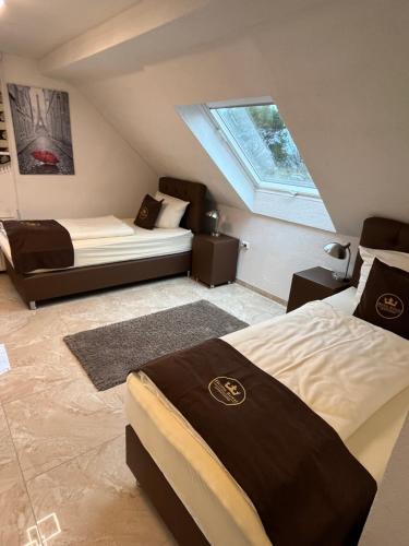 a attic bedroom with two beds and a window at Hotel Royal in Leopoldshöhe
