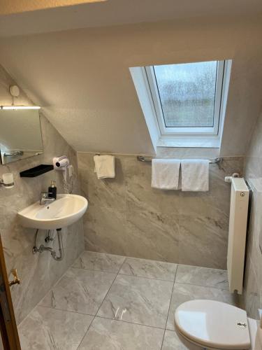 a bathroom with a sink and a toilet and a window at Hotel Royal in Leopoldshöhe