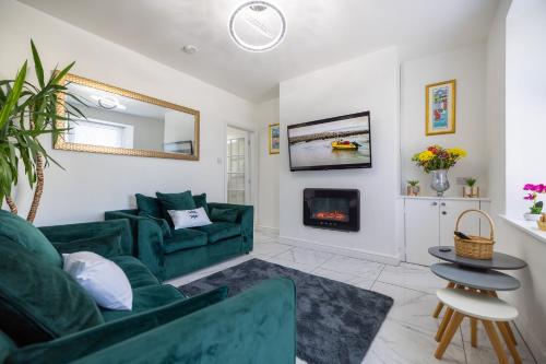 a living room with a green couch and a fireplace at The Bay Cottage Hot Tub & Sauna Morecambe Bay in Morecambe