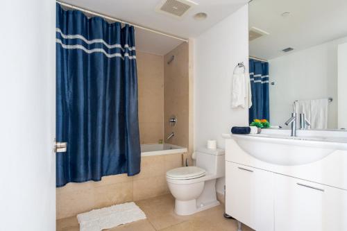 a bathroom with a blue shower curtain and a toilet at Icon Brickell W Residences in Miami