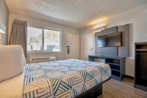a hotel room with a bed and a flat screen tv at Motel 6 Santa Fe in Santa Fe