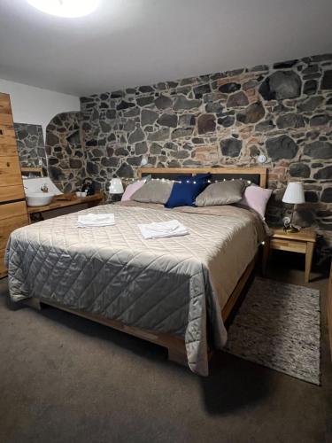 1 dormitorio con 1 cama grande y pared de piedra en ŠTAJNHAUS DUBICE 
