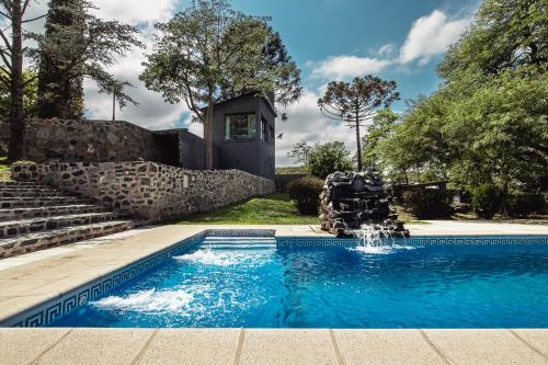 a swimming pool with a fountain in a yard at El Refugio Apart in Villa Serranita
